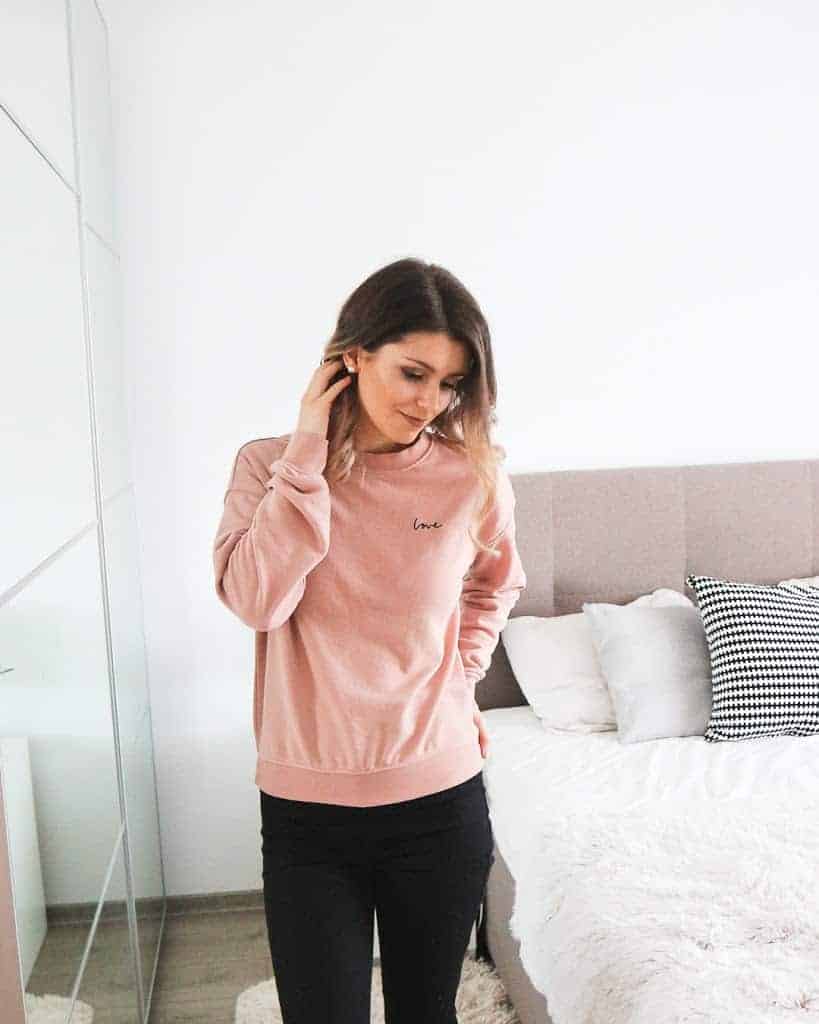 H&M pink love jumper with black pants and black trainers outfit